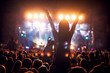 Silhouette of a girl at a concert holding her hand up and having fun.