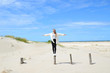 junge Frau balanciert auf einem Holzpfahl am Meer, Rømø, Dänemark, work-life-balance
