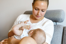 Caring Young Mother Breastfeeds Baby Girl