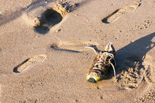 Old Abandoned Wet Dirty Shoe On Beach Sand