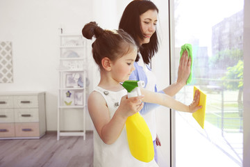 Daughter and mother cleaning window together