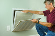 © Michael O'Keene - Professional repair service man or diy home owner removing a dirty air filter on a house air conditioner so he can replace it with a new clean one.