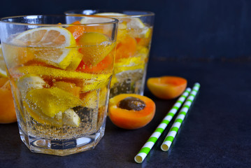 Cold, Summer lemonade with peach and apricot on the black backgr