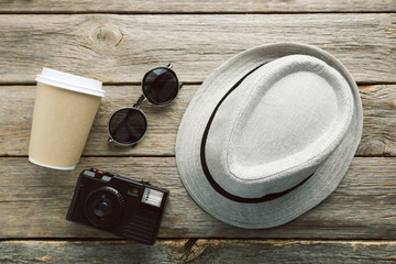 Wall Mural - Pretty hat with sunglasses, camera and drinking cup on wooden ta