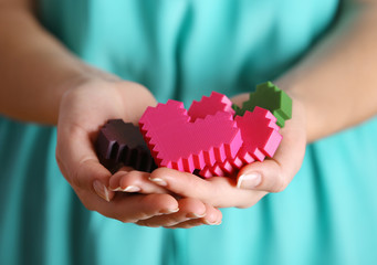 Wall Mural - Closeup of plastic puzzle hearts in female hands