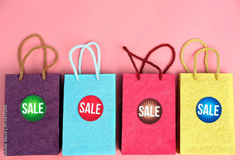 Paper shopping bags with tags on pink background