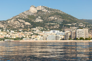 Wall Mural - Luxury homes on the rocky Mediterranean coast of the French Riviera at Monte Carlo in Monaco, with mountain in the background. Horizontal with copy space for text