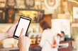 © tortoon - Hand using smartphone and Blurred background in coffee shop. vin