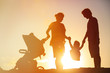 Happy family with little child and stroller play at sunset