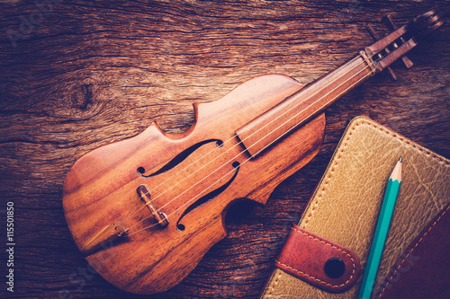 Obraz Dibond Violin and notebook with pencil on grunge dark wood background
