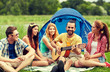 © Syda Productions - happy friends with drinks and guitar at camping