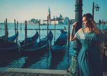 Beautiful Well-dressed Woman Standing Near San Marco Square With Gondolas And Santa Lucia Island On The Background. 