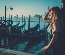 Beautiful Well-dressed Woman Standing Near San Marco Square With Gondolas And Santa Lucia Island On The Background. 