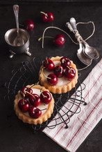 Tartlets Filled With Cream And Cherries For Tea Time In Dark Background