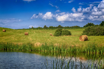 haystacks on the field with a pond in Poland