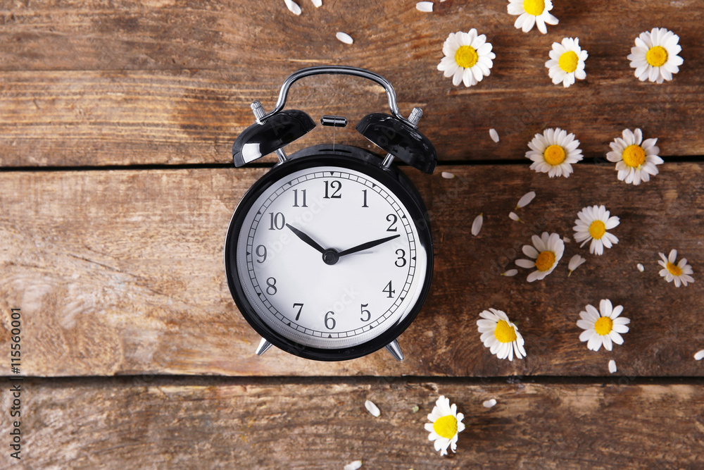 Vintage clock and daisy flowers on wooden background