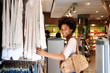 © mimagephotos - Smiling woman shopping in clothing store