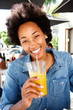 © mimagephotos - Smiling woman drinking orange juice at cafe