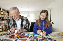 Grandfather And Granddaughter Coloring Eggs At Home