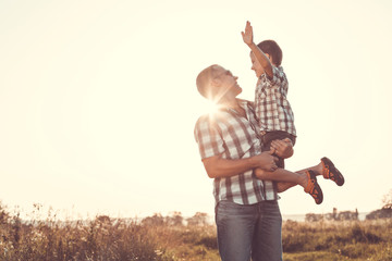 Wall Mural - Father and son playing in the park at the sunset time.