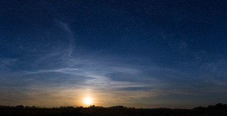 rising moon in dark blue sky with stars