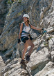 © XtravaganT - Smiling female hiker on rock face looking back