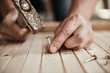 Close-up of handyman hammering a nail in wooden board. Concept of repair and renovation. 