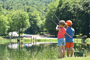 Wall Mural - Kids fishing by mountain lake in summer