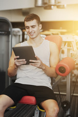 Canvas Print - smiling young man with tablet pc computer in gym