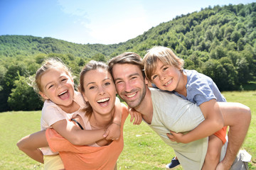 Wall Mural - Parents giving piggyback ride to kids in mountains