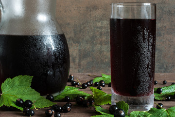 Wall Mural - cold black currant juice in a glass and pitcher on wooden table