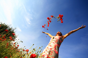 femme joyeuse qui lance des coquelicots en l'air