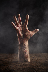 Human hand in blood and dirt on dark background