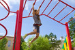 Little girl playing on a playground, hanging walk along the monkey bars