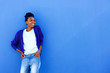 Happy young african female standing against blue wall