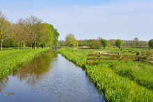 Classic Dutch Landscape. Polder Ditch Canal On A Green Grass Field.