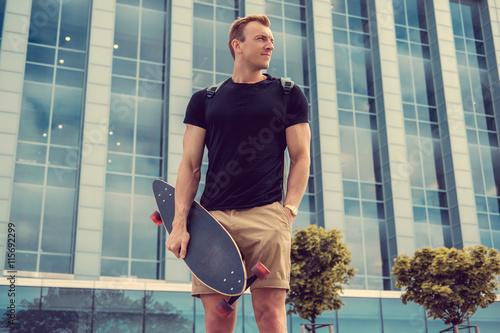 Fototapeta na szkło Dorywczo miejski mężczyzna trzyma longboard.