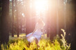 © dizfoto1973 - Beautiful young woman wearing elegant light blue dress standing in the forest with rays of sunlight beaming through the leaves of the trees. Soft focus and Toning