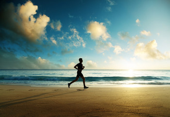 Wall Mural - Man running on tropical beach at sunset