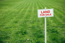 Land For Sale Sign Against Trimmed Lawn Background
