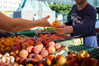 © Astrakan Images - Vendor selling peach to girl at market