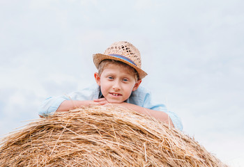 Wall Mural - Boy in straw hat lying on the haystack