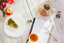 Datebook, Flower, Cup Of Tea, Chicken Pie, Apple, Glass Teapot And Watch On Wooden Table