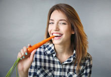 Beautiful Girl Eating Carrot On Grey Background