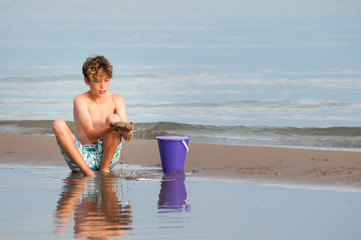 young boy playing on a sandy beach on a summer day