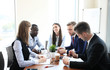 © ty - Young handsome woman gesturing and discussing something while his coworkers listening to him sitting at the office table