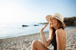 © Cookie Studio - Beautiful young cheerful girl in hat rests at morning beach