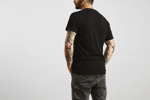 Brutal Attractive Bearded Biker Man With Tattooed Hands Poses Backside In Black Blank T-shirt From Premium Thin Cotton, Isolated On White Mockup