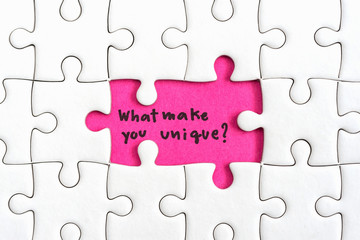 Jigsaw puzzle piece with two missing and hand writing letters word what make you unique and question mark Quotes business concept