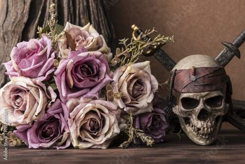 Bouquet purple roses with pirate skull and two swords over tree background on...